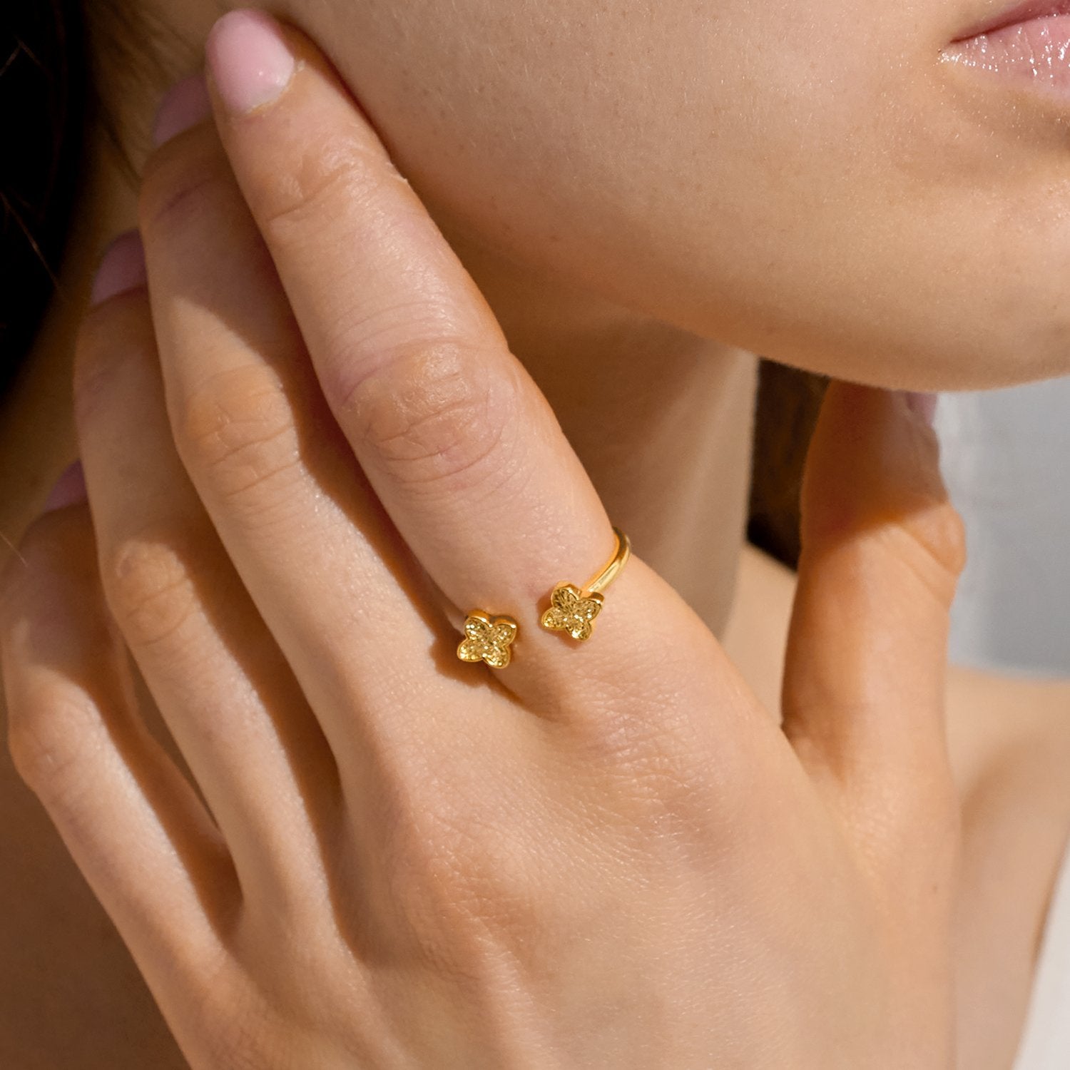 Close-up of a hand wearing a gold ring with a clover design.