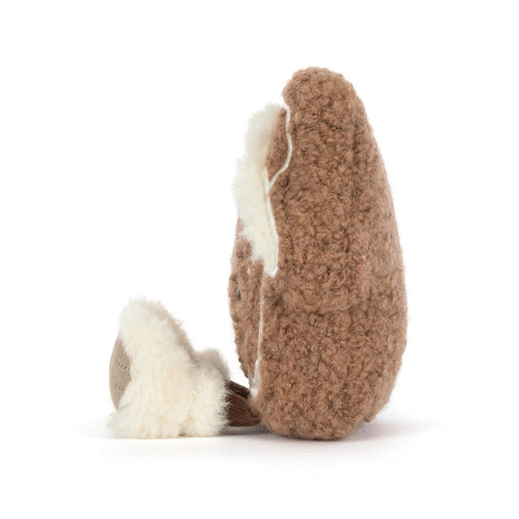 Amuseables Molasi Cookie plush toy shown from the side on a clean white background. The toy features a fluffy cream-colored inner lining and a small matching cream tail.