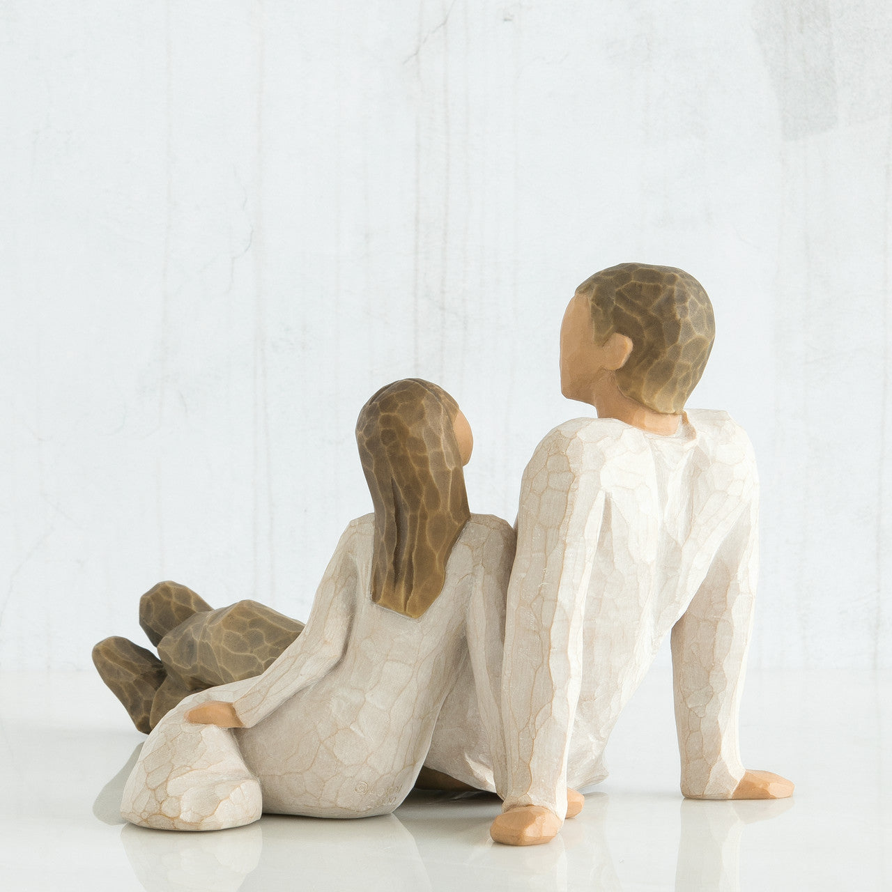 willow tree figurine of a father and his daughter sitting together on a white background