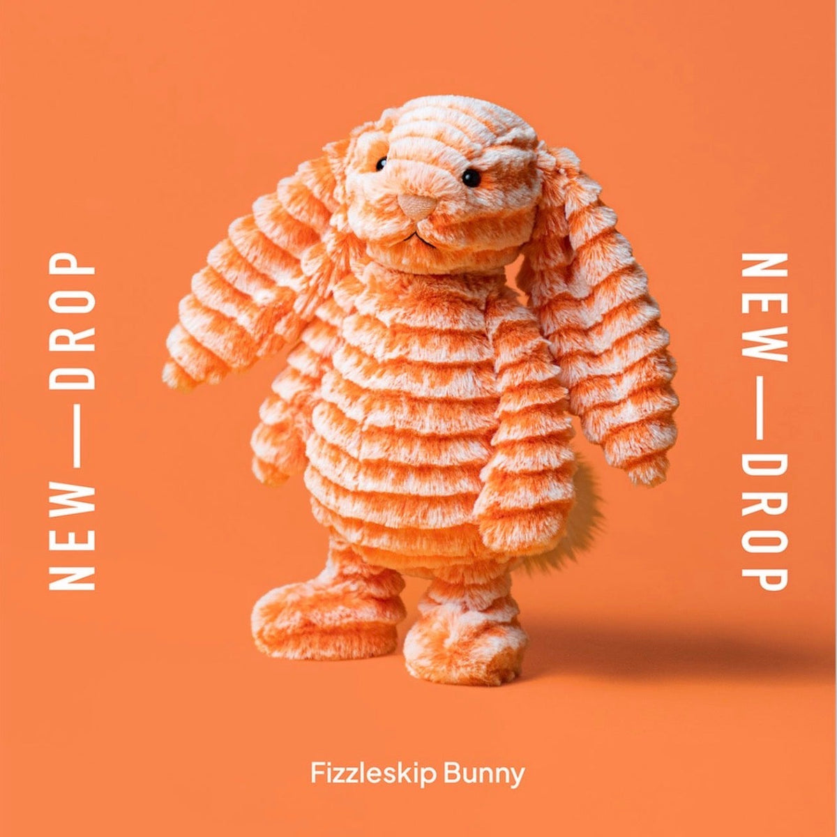 An orange Fizzleskip jellycat bunny with textured, layered fur stands centered on a solid orange background. White vertical text on both sides reads 'NEW - DROP', and white text at the bottom reads 'Fizzleskip Bunny'.