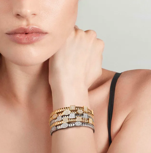 Close-up of a woman's hand wearing multiple nomination Extension collection bracelets on a neutral background
