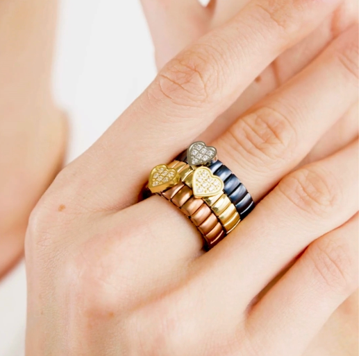 Stack of nomination Italy extension collection gold plated and silver rings. On a finger against a neutral background showcasing the product