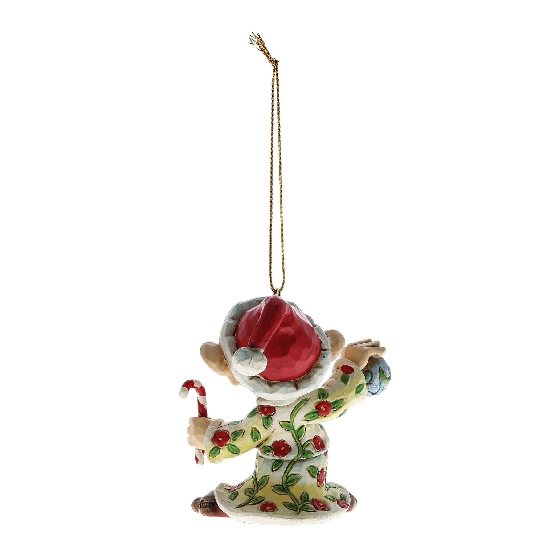 A ceramic Christmas ornament depicting a gnome in a red Santa hat and green holiday pajamas with red berry patterns, holding a candy cane, suspended by a gold string on a white background.