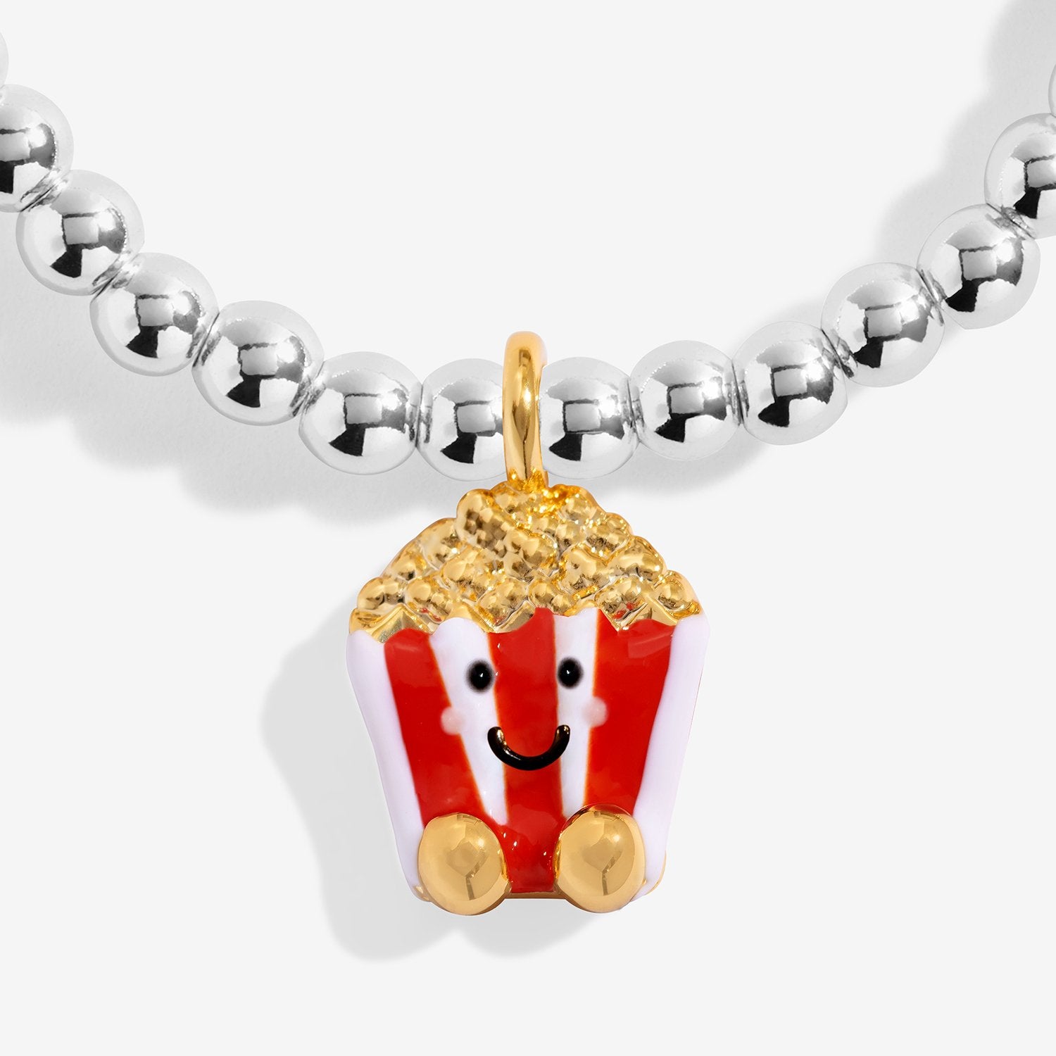 A silver-plated beaded bracelet featuring a cute, smiling popcorn character charm. The charm has red and white striped sides, a gold top loop, and gold feet, with yellow glittery popcorn details on top.
