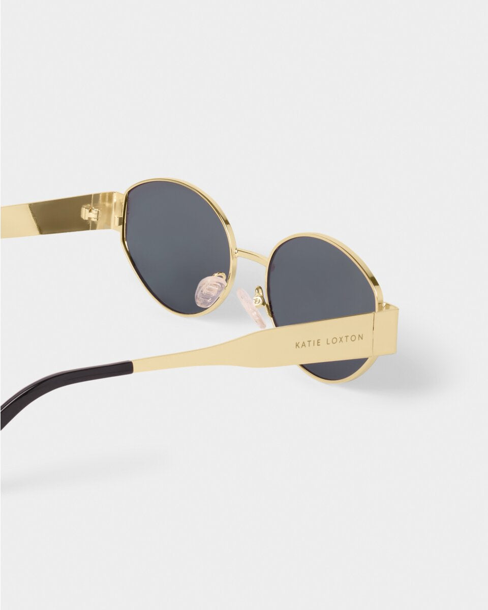 katie loxton Gold-framed sunglasses with black lenses on a white background