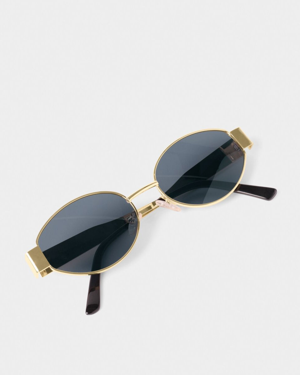 katie loxton Gold-framed sunglasses with black lenses on a white background