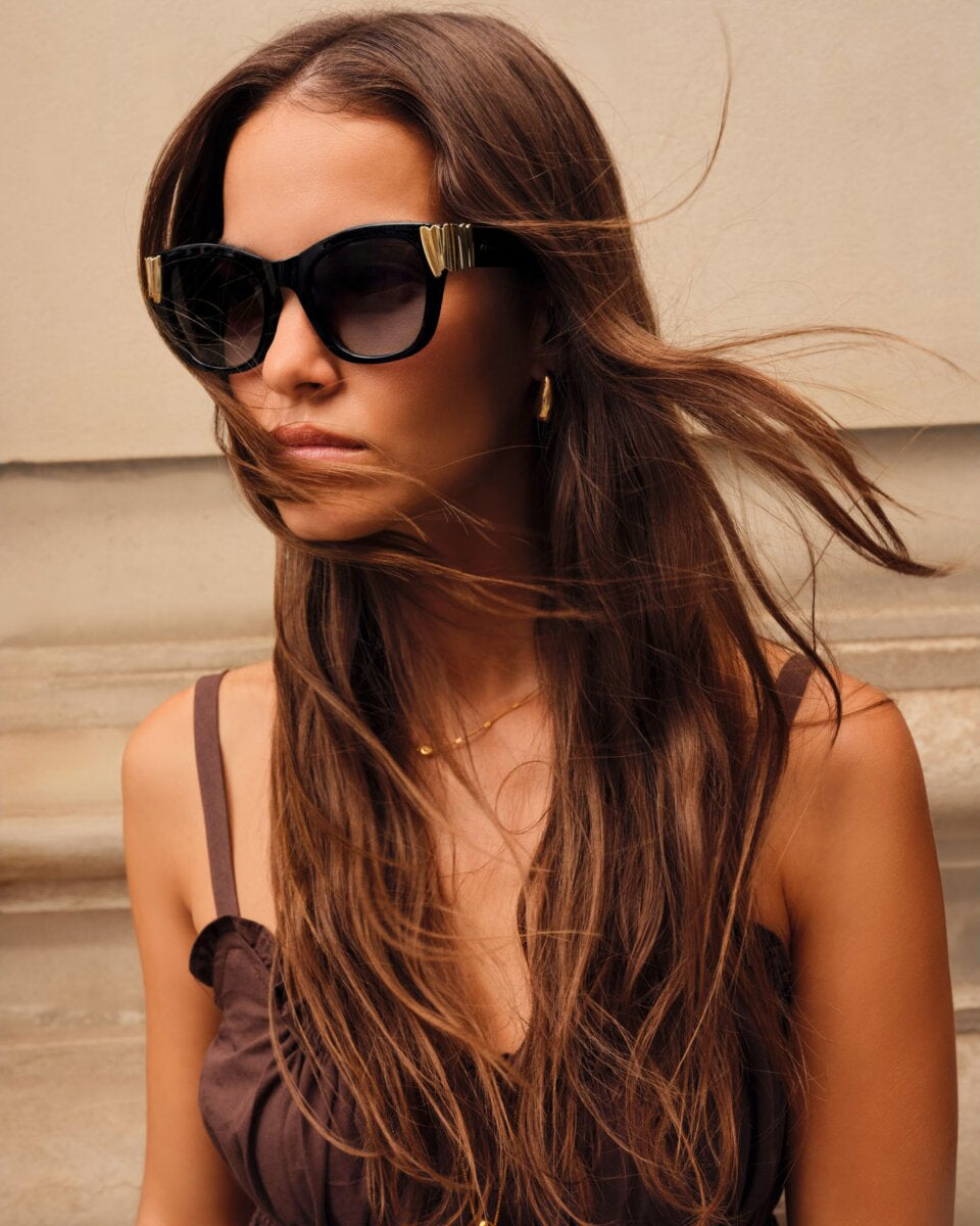 Woman wearing Black seychelles round sunglasses with a neutral background