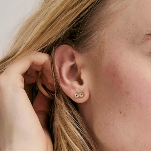 Close-up of an models ear wearing a gold coloured nomination Italy infinity stud