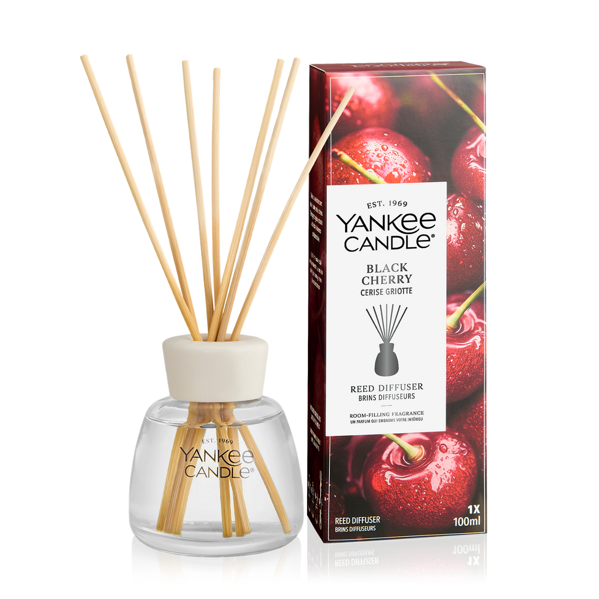 Yankee Candle Black Cherry reed diffuser with natural reed sticks in a clear glass bottle, shown next to its retail box featuring a glossy red cherry design.