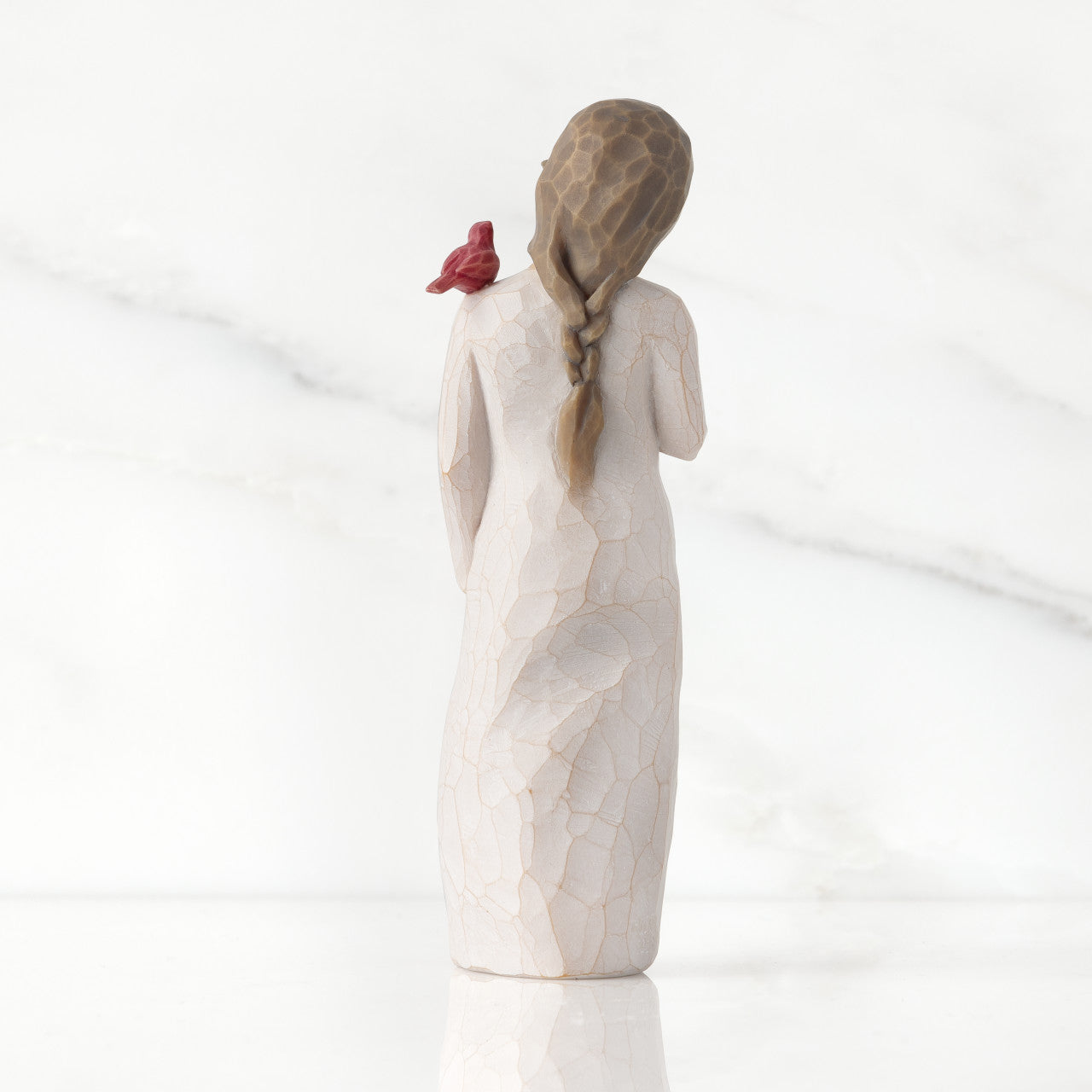 willow tree figurine of a woman with braided hair and a red bird on a white background