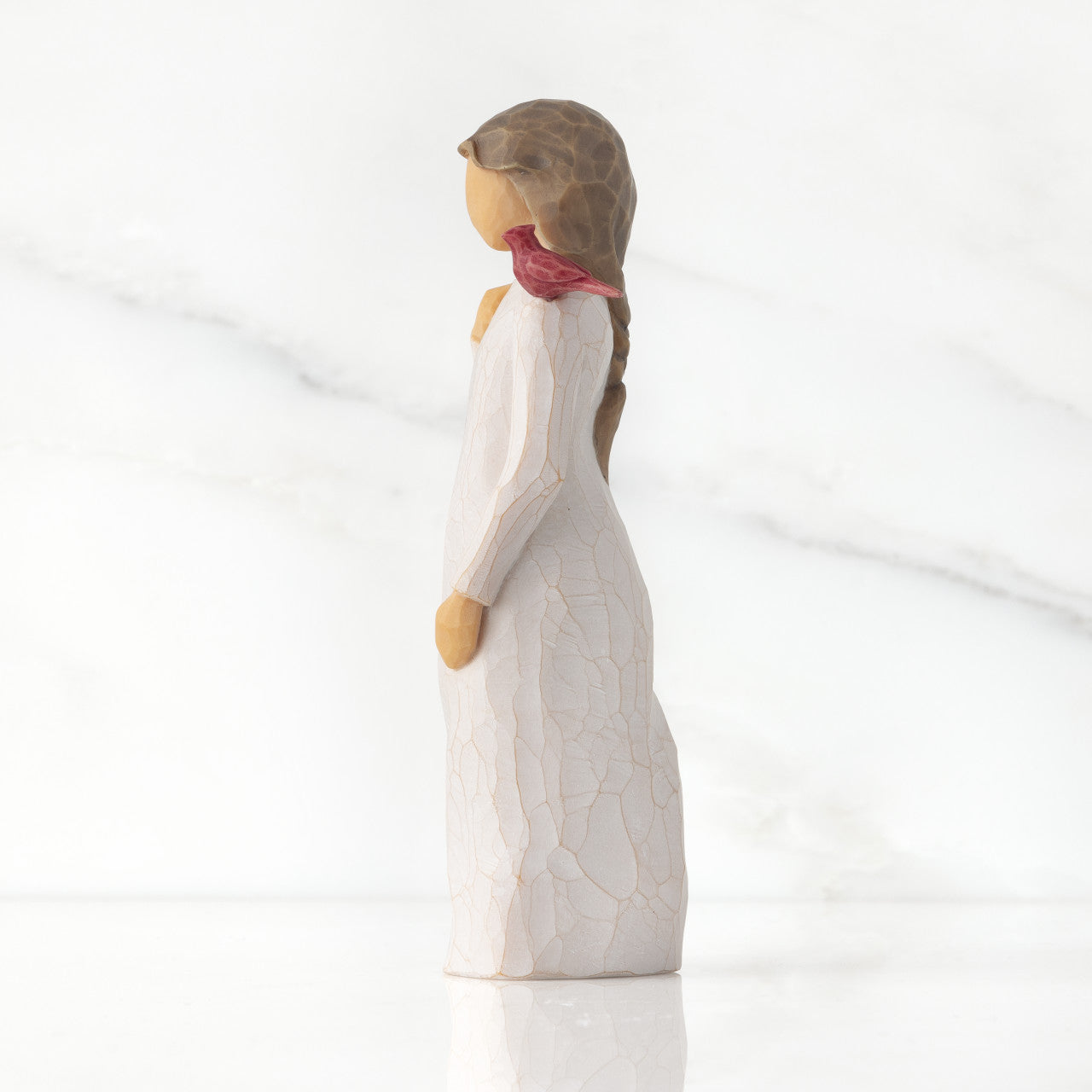 willow tree messenger figurine of a woman with a white dress and red bird on a light gray background