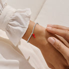 joma jewellery Bracelet with a red charm on a wrist against a neutral background