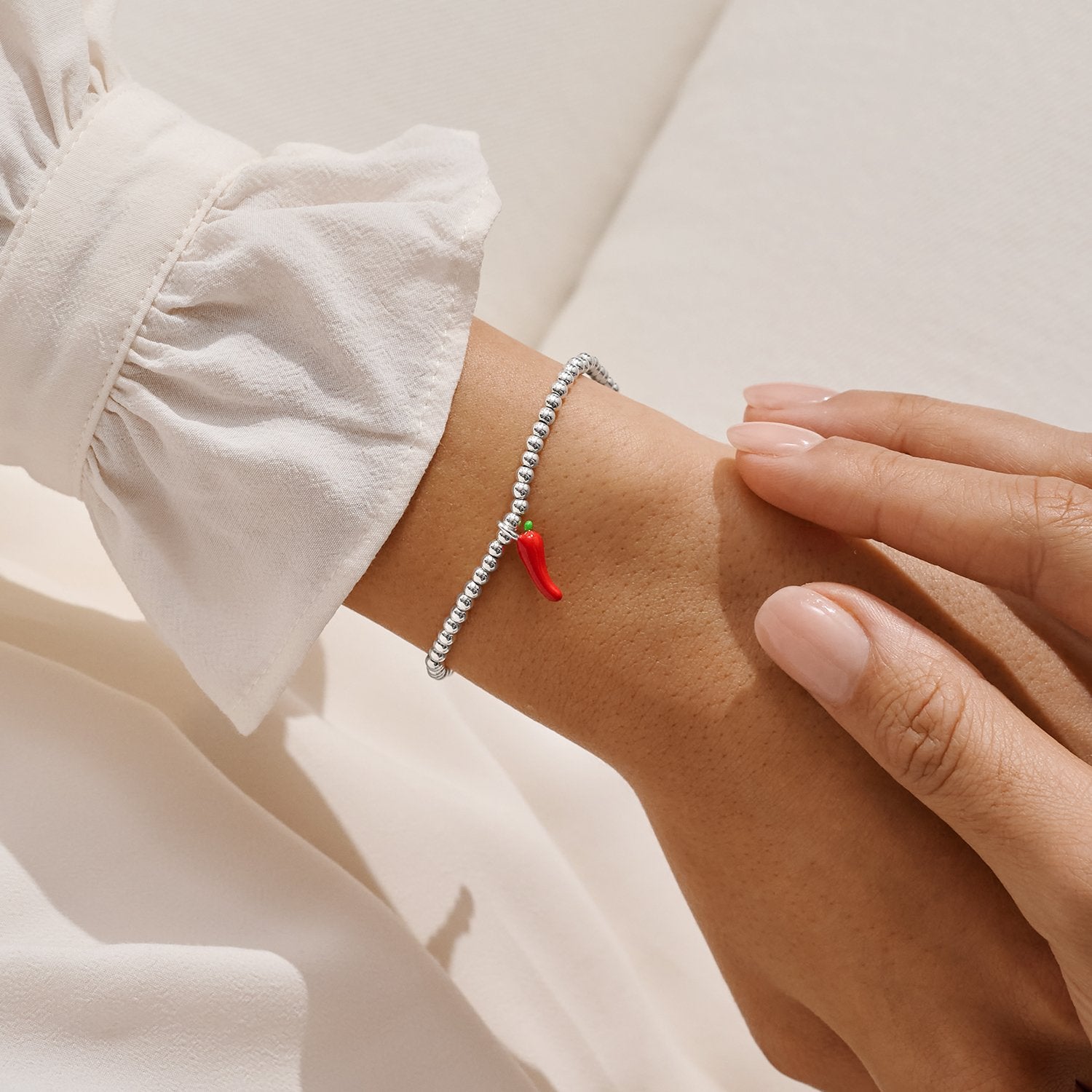 joma jewellery Bracelet with a red charm on a wrist against a neutral background