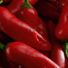 Close-up of red chili peppers with a small red chili pepper charm. which features on the Spice of life joma bracelet.