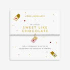 A Joma Jewellery 'A Little Sweet Like Chocolate' bracelet displayed on its white gift card. The bracelet features a silver-toned beaded chain with a pink and red heart on a chocolate bar charm.