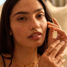 Close-up of a woman wearing the clover collection. Image feature the red clover ring  set against a neutral background.