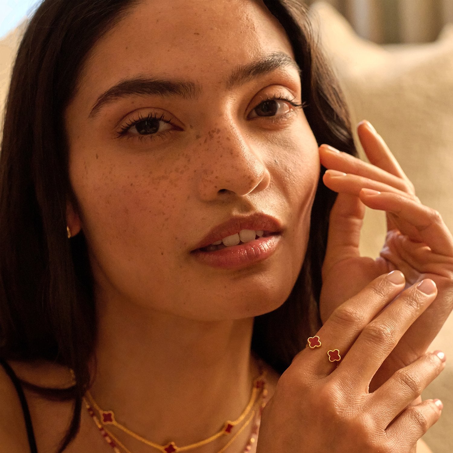 Close-up of a woman wearing the clover collection. Image feature the red clover ring  set against a neutral background.