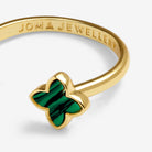 A gold-plated ring featuring a four-petal flower setting with a vibrant green enamel inlay, shown on a clean white background. The inside of the band is engraved with the brand name 'JOMA JEWELLERY'.