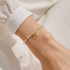 Close up of a person's wrist wearing a Joma Jewellery bracelet with glasses 