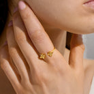 Close-up of a hand wearing a gold ring with a clover design.