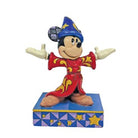 A figurine of Sorcerer Mickey Mouse wearing a red and blue outfit with gold accents, standing on a base with blue and yellow stars.