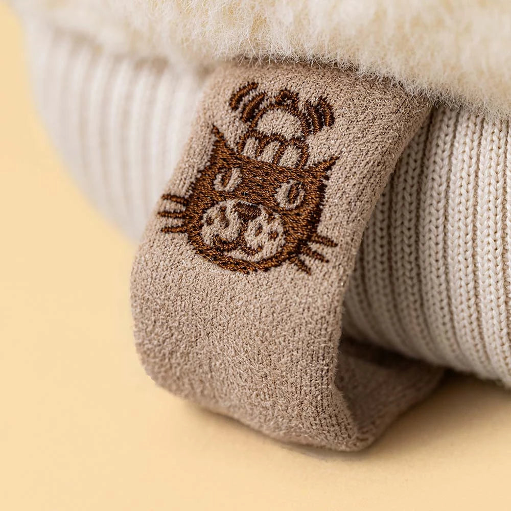 Close up of Jellycat amuseable mitten showing the brands logo on a tag