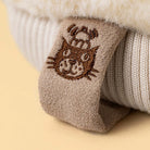 Close up of Jellycat amuseable mitten showing the brands logo on a tag