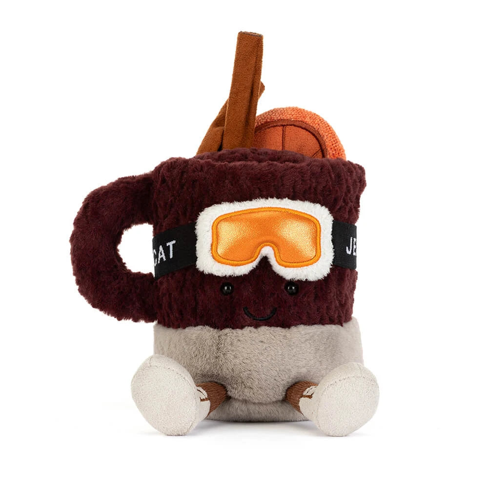 Jellycat amuseables spiced drink with a smiling face, wearing orange goggles and brown boots, on a solid white background.