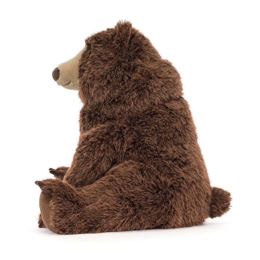 Jellycat bizzlestomp plush brown bear toy sitting upright, photographed from the side against a clean white background.