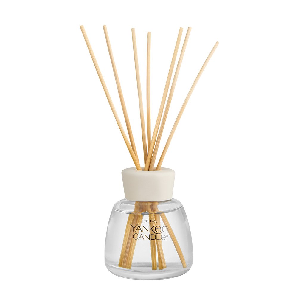 Yankee Candle reed diffuser with a clear glass bottle, cream-colored cap, and natural bamboo reeds, shown on a solid white background.