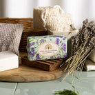 Bar of English Lavender soap on a wooden tray with lavender flowers and a woven basket in the background.