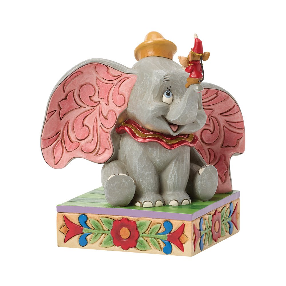 Decorative Dumbo elephant figurine with pink ears sat on a colourful base with white background