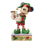 Mickey mouse character figurine dressed as an elf holding a small train on a white background