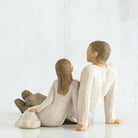willow tree figurine of a father and his daughter sitting together on a white background