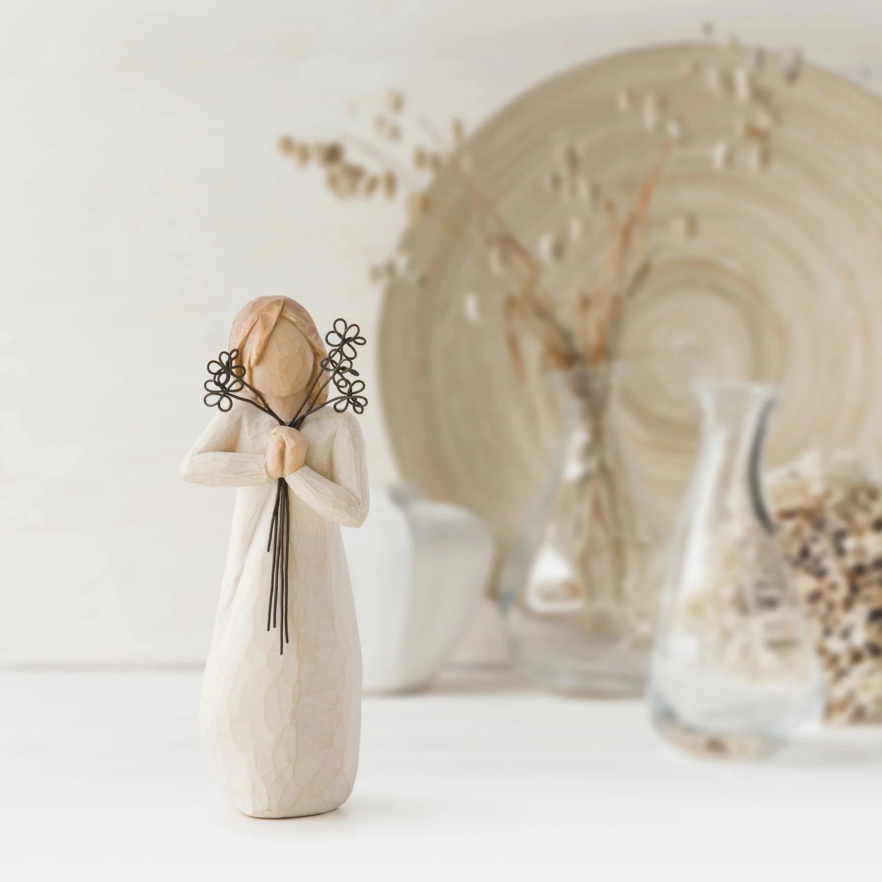 willow tree friendship figurine holding a floral arrangement against a neutral background