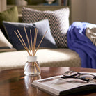 Yankee Candle diffuser on a coffee table with a magazine and glasses in a cozy living room.