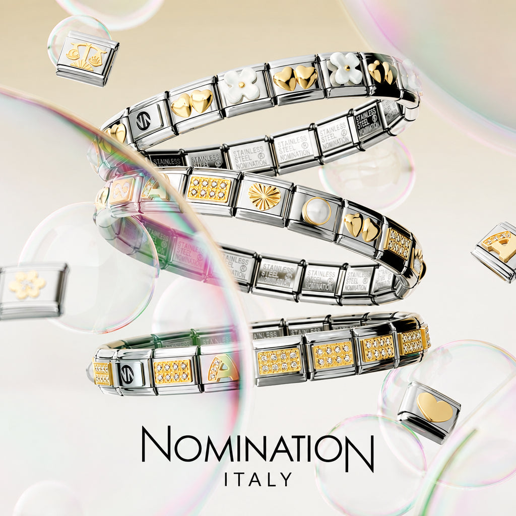 Three silver-toned Nomination Italy charm bracelets featuring  yellow gold links from the composable Nomination charm collection. Spiral on a soft cream background with floating bubbles and the text 'NOMINATION ITALY' at the bottom.