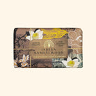 Bar of soap with decorative packaging featuring floral designs and branding text on a beige background.