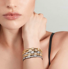 Close-up of a woman's hand wearing multiple nomination Extension collection bracelets on a neutral background