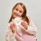 Young girl holding a sprinkle kindness everywhere childrens jomee bracelet. On its presentation gift card with text against a plain background