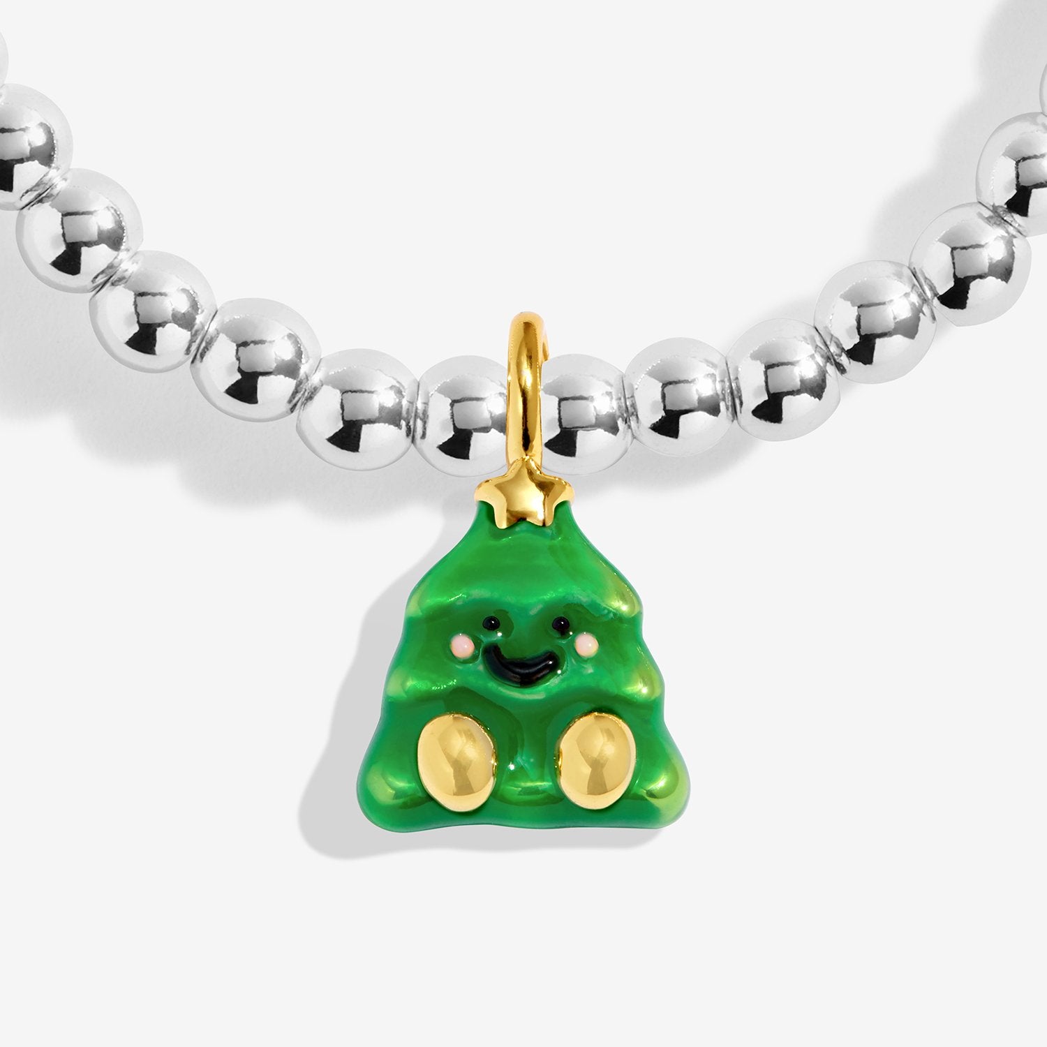 A close-up of the jomee's joma jewellery charm with shiny a green Christmas tree pendant with gold accents, shown on a light gray background.