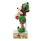 Mickey mouse dressed as elf holding a train in his hands facing side on 