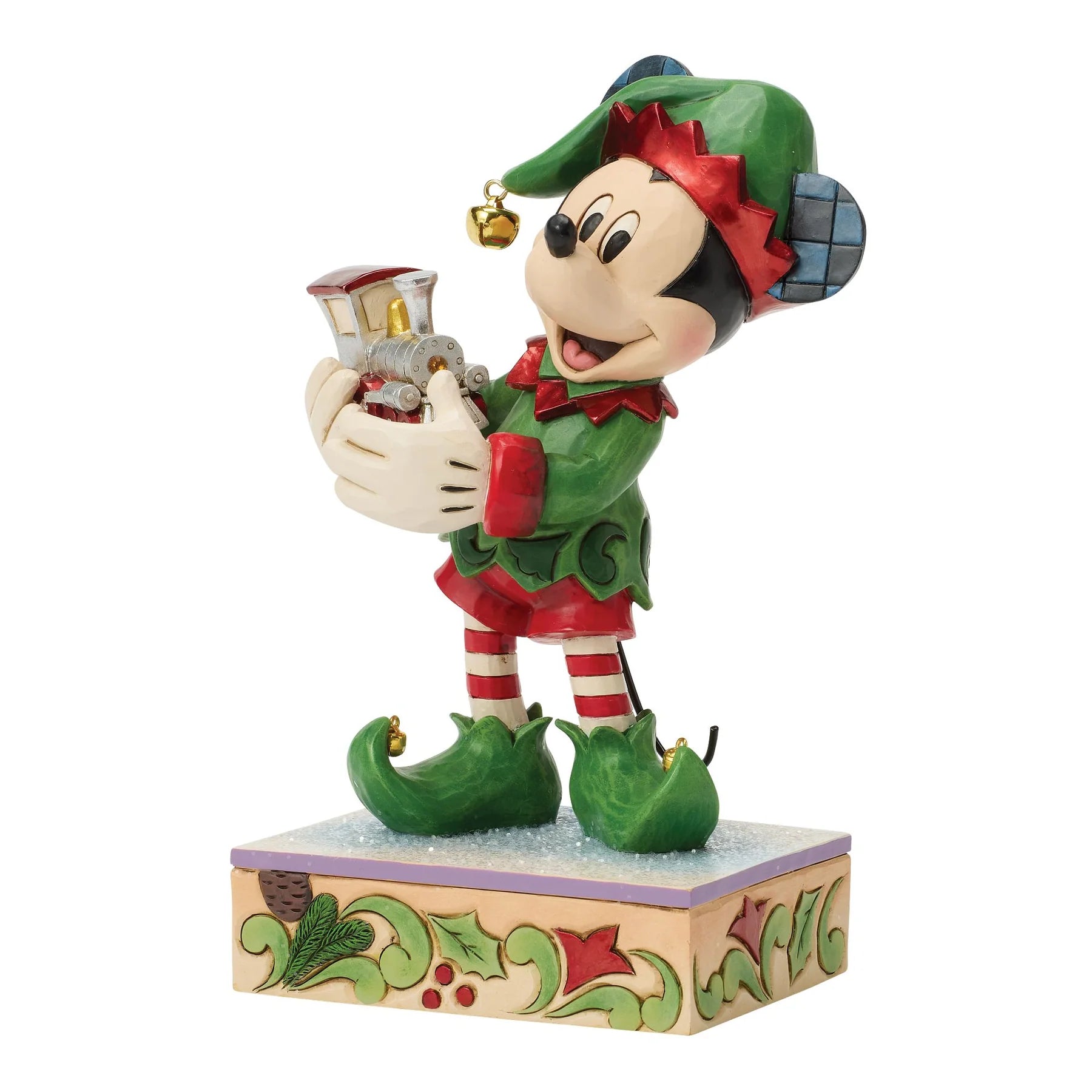 Mickey Mouse figurine dressed as a Elf holding a toy train in his hands on a decorative base. 