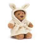 A plush jellycat Bartholomew teddy bear wearing a cream-colored hooded bathrobe, photographed against a clean white background.