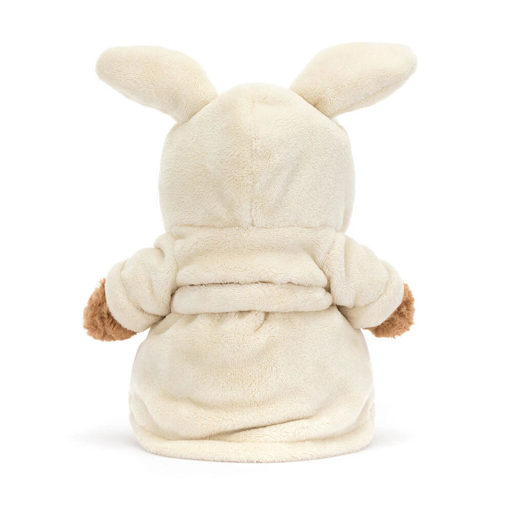 Plush jellycat Bartholomew teddy bear wearing a cream bathrobe on a white background