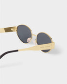 katie loxton Gold-framed sunglasses with black lenses on a white background