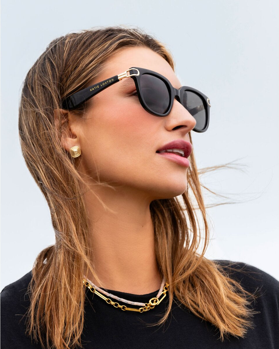 Woman wearing black Manhatten Katie Loxton sunglasses sunglasses with a blurred background