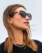 Woman wearing black Katie Loxton Manhattan sunglasses with a blurred background