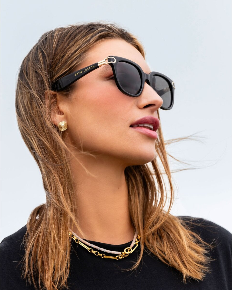 Woman wearing black Katie Loxton Manhattan sunglasses with a blurred background
