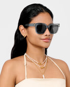 Woman wearing katie loxton roma sunglasses with a plain background